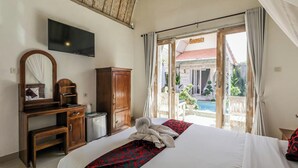 A hotel room with a bed, a desk, a television, and a view of a pool and outdoor area. - The Box Paradise Bungalow (Penida Island)