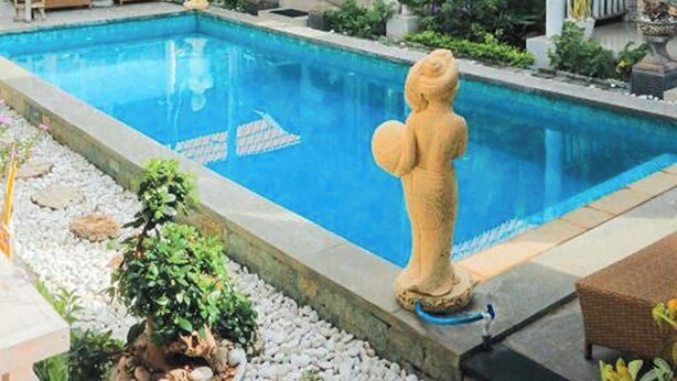 A pool area with a statue, lounge chairs, and a covered seating area with a tiled roof. - The Box Paradise Bungalow (Penida Island)