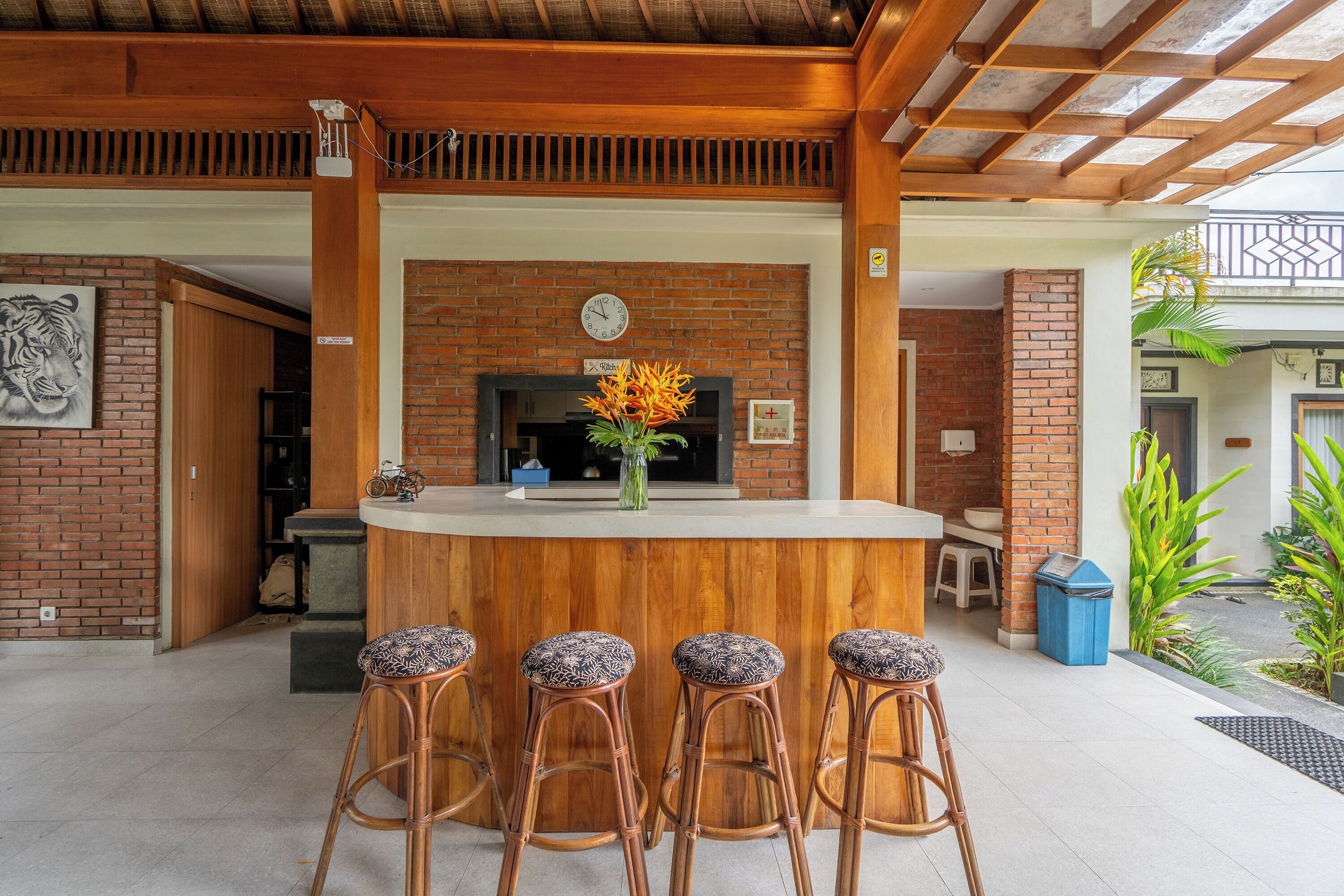 A wooden bar area with a brick wall, a clock, and a vase with flowers.