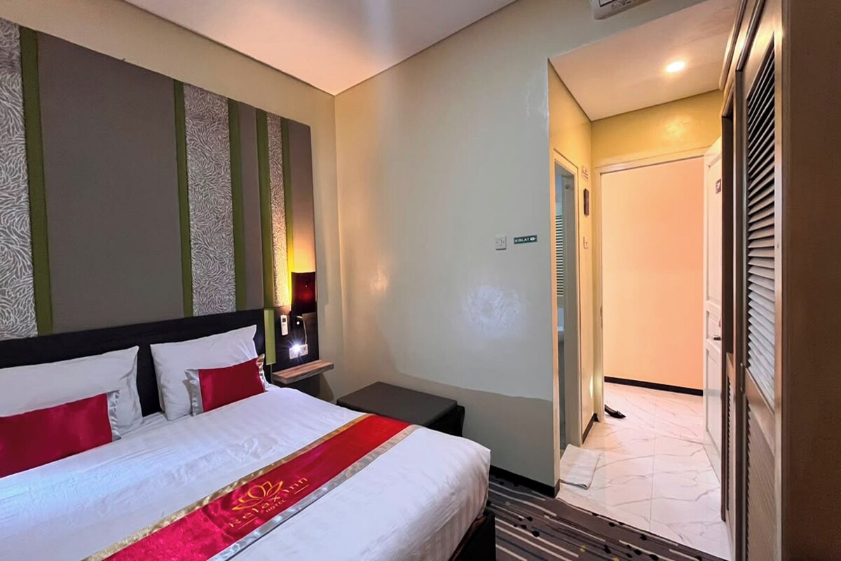 Een hotelkamer met een bed, nachtkastje en een deur naar een badkamer.