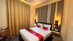 Quarto de hotel com uma cama grande, uma escrivaninha e uma cadeira.