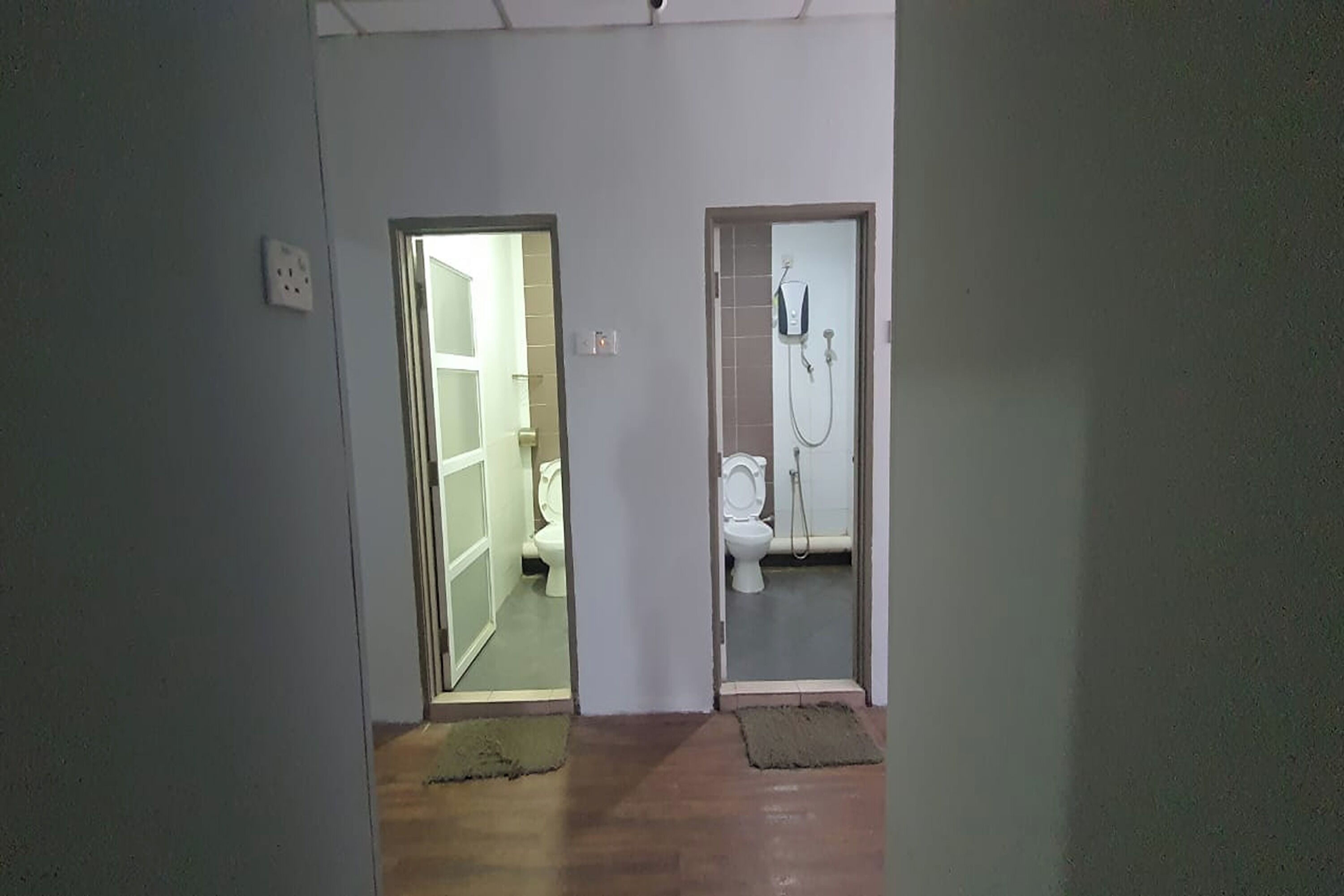 Un couloir avec deux portes donnant accès à une salle de bain et à des toilettes.