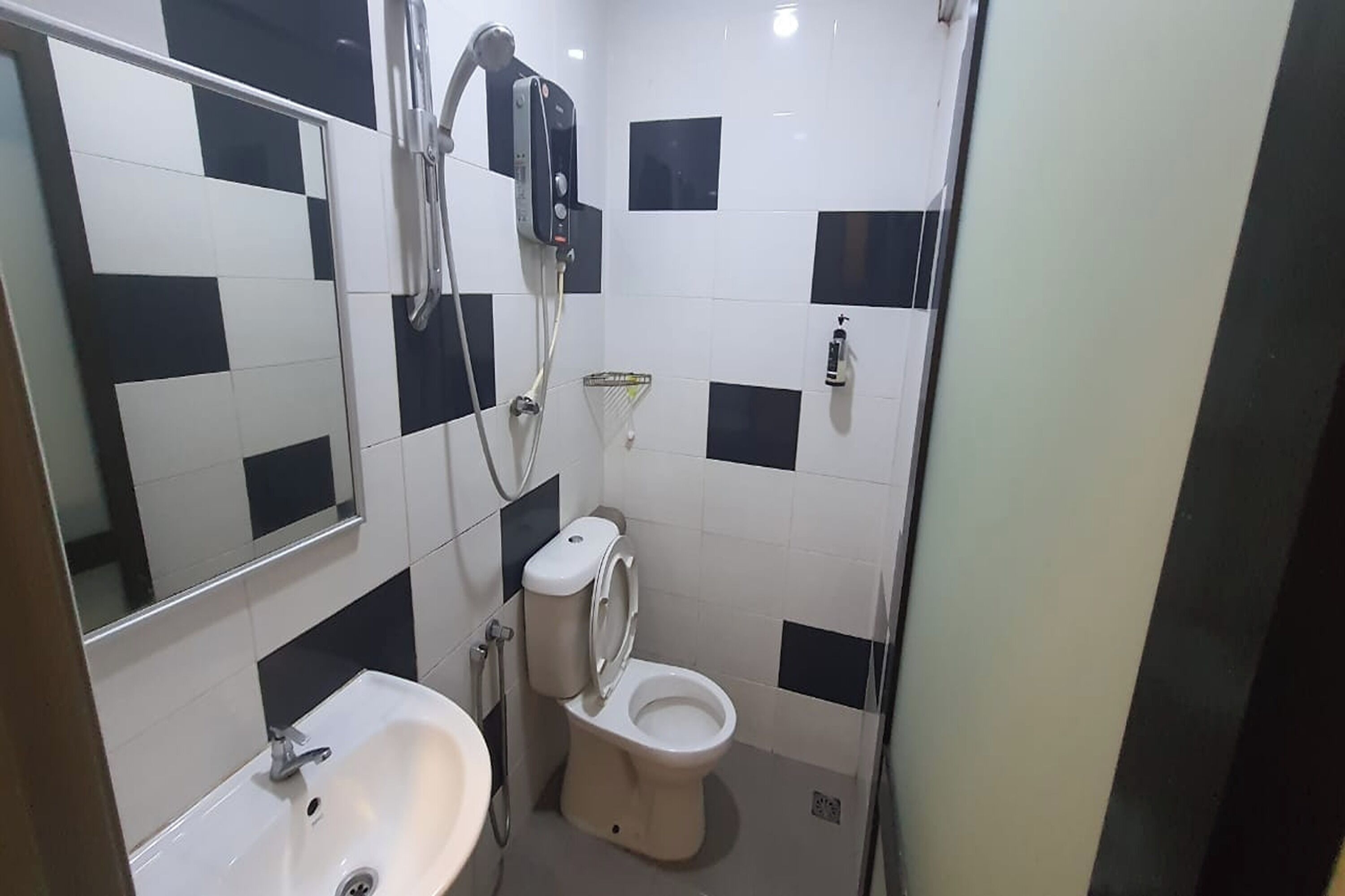 A bathroom with a sink, toilet, and a shower unit.