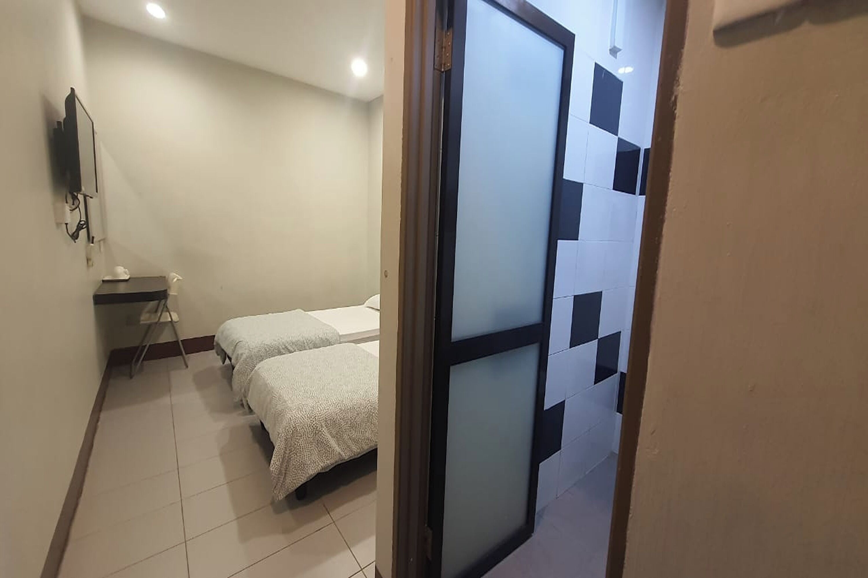 A hotel room with two beds, a desk, and a television.