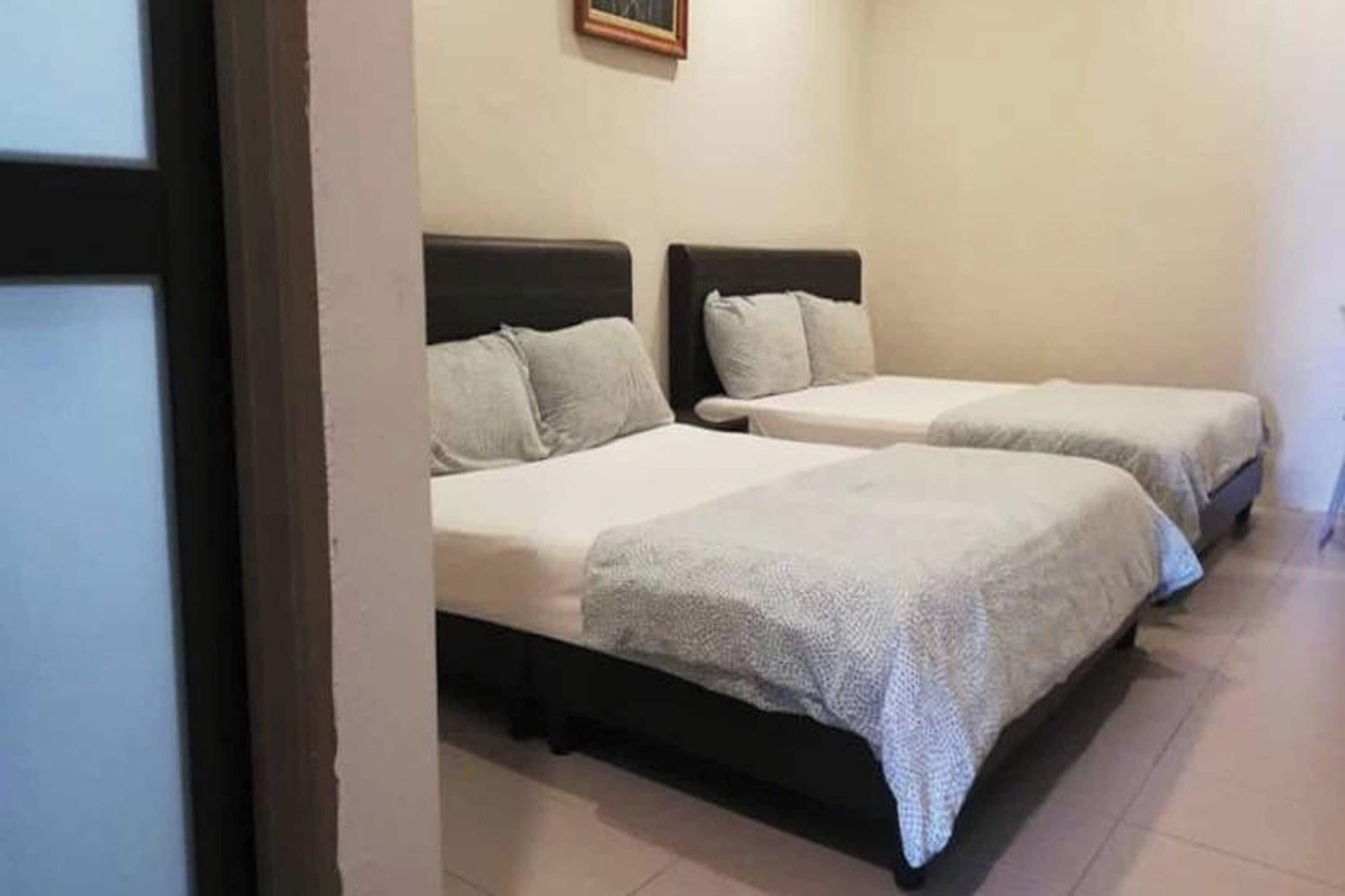 A room with two beds, each with a headboard and pillows.