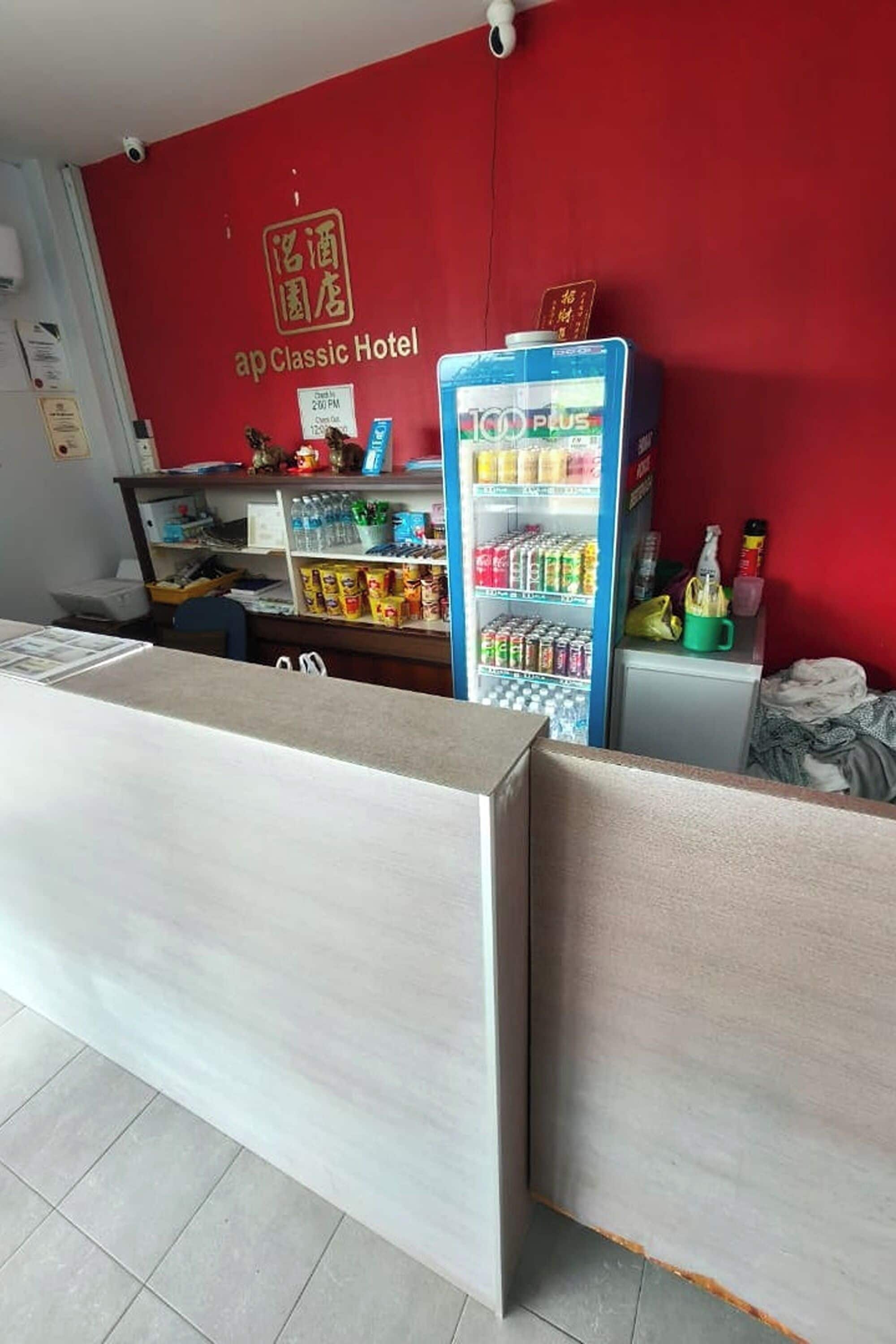 Un espace d’accueil avec un mur rouge, un comptoir de réception, un distributeur automatique et une caméra de surveillance fixée au mur.