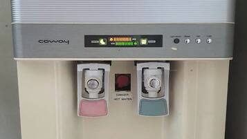 Een waterdispenser met een digitaal scherm, twee tappen voor warm en koud water, en een knop om water te tappen.