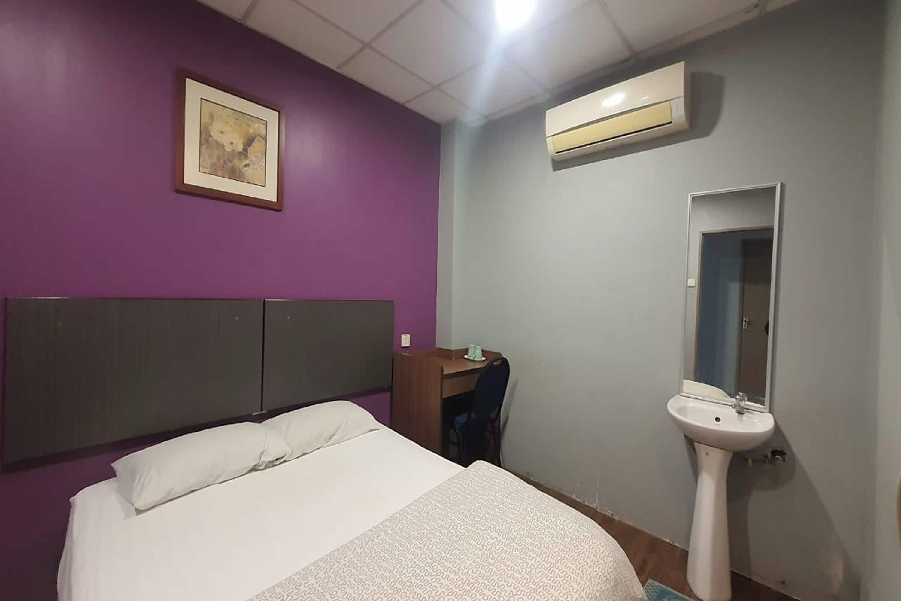Une chambre d’hôtel équipée d’un lit, d’une table de chevet, d’un miroir et d’un climatiseur fixé au mur.