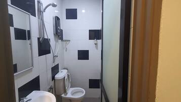 Une petite salle de bain avec un lavabo blanc, des toilettes et un espace douche.