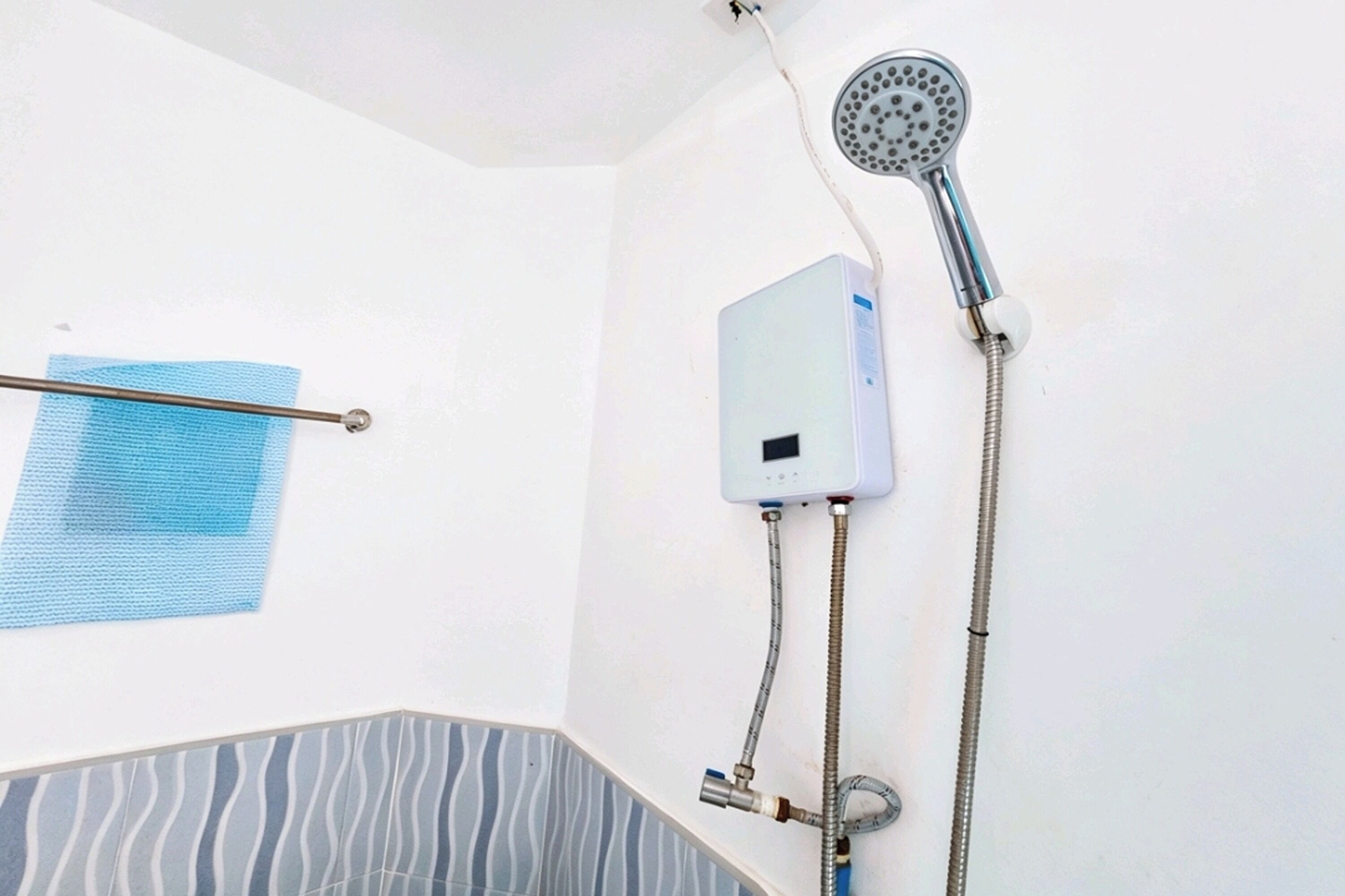 A bathroom with a shower, a towel rack, and a water heater.