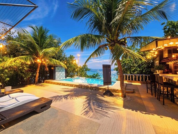 A poolside area with a view of the ocean, palm trees, and a bar area. - Ffg Eden Private Resort (Moalboal)