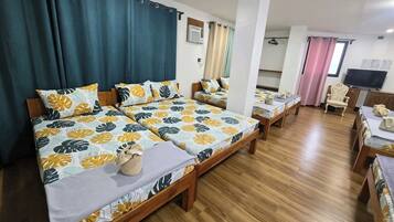 Een hotelkamer met twee bedden, houten vloeren, een televisie en een stoel.