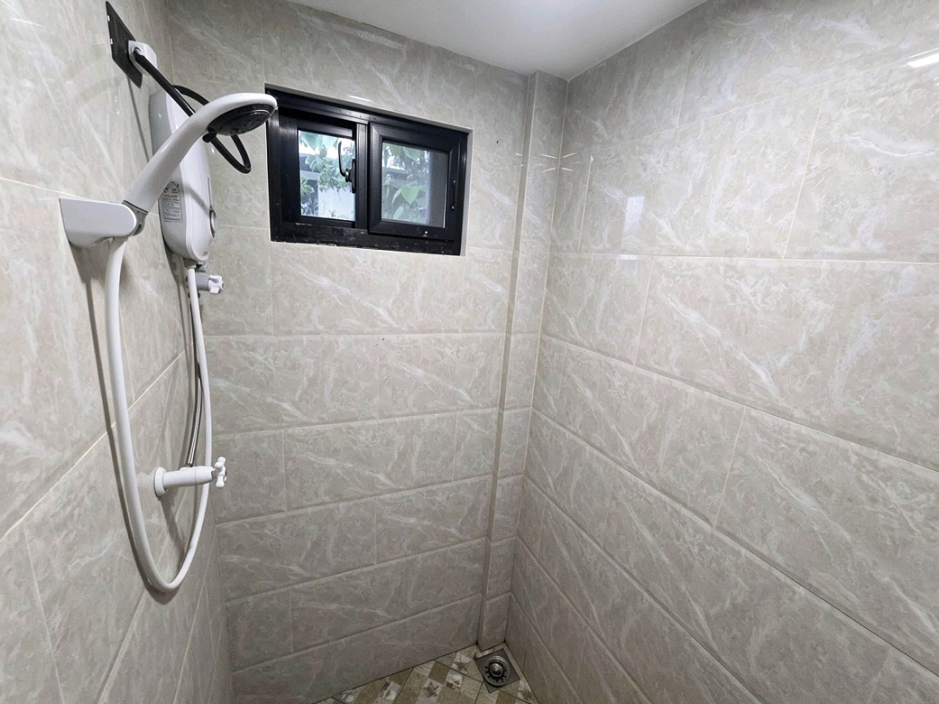 A small, enclosed shower area with a handheld showerhead and a window.