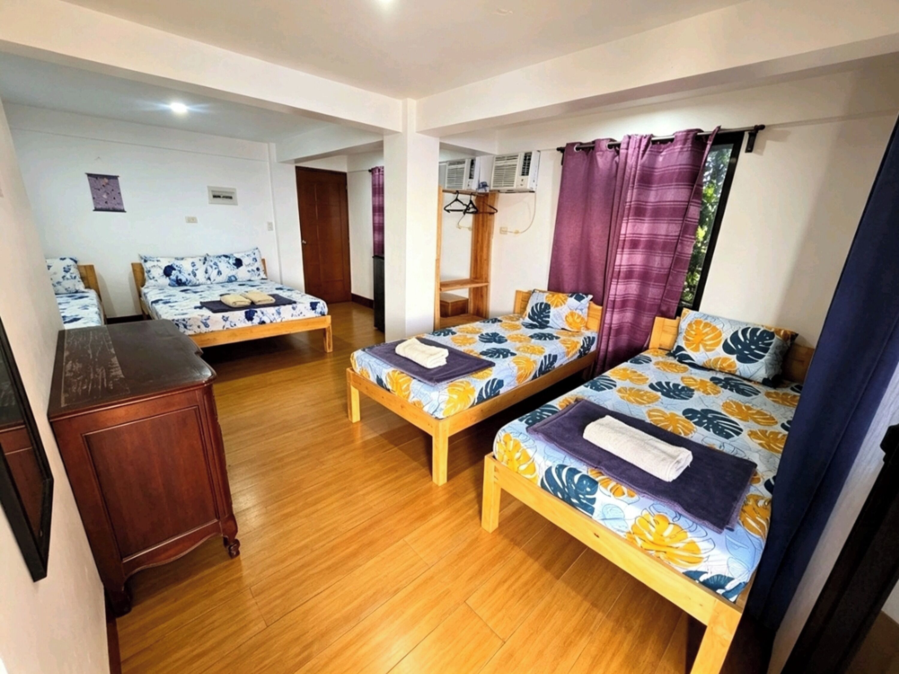 A room with two wooden beds, a wooden dresser, and a small table.