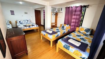 A room with two wooden beds, a wooden dresser, and a small table.