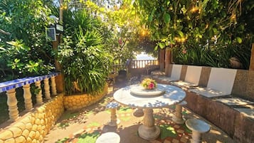 A patio with a round table and stools, surrounded by a stone wall and potted plants.