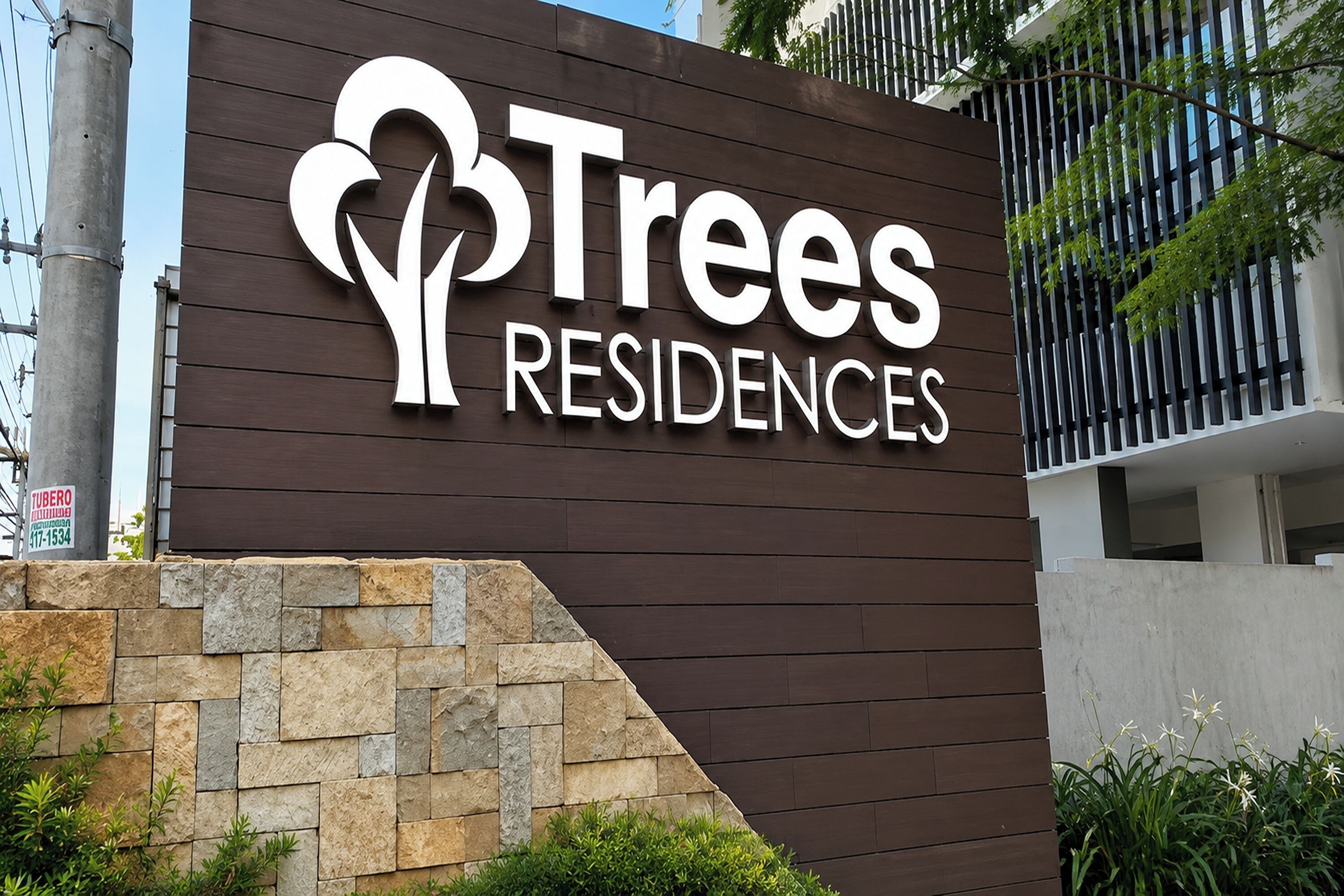 Segnaletica per Trees Residences, caratterizzata da un design moderno e un muro di pietra antistante.