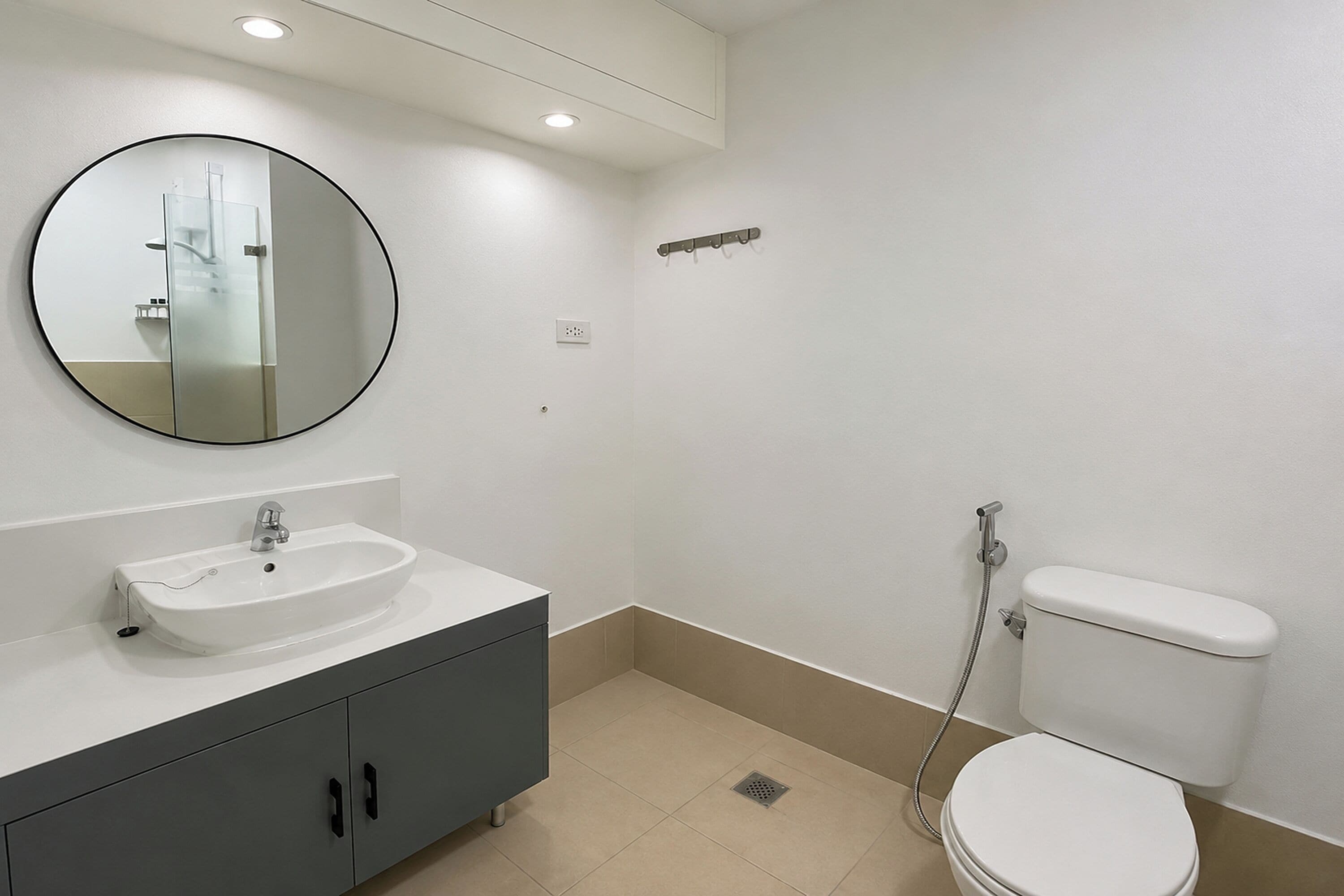 Une salle de bain avec un miroir rond, un lavabo, des toilettes et une douche.