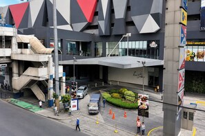 Ein modernes Gebäude mit einer einzigartigen, geometrischen Fassade, einem überdachten Eingang und einer begrünten Anlage mit Pflanzen.