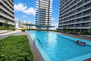 Ein Swimmingpool, umgeben von modernen Gebäuden, mit blauem Himmel darüber.