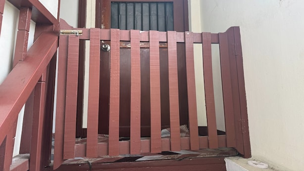 A red metal gate with a latch, leading to a staircase. - Sleep Break Hostel Sathon (Bangkok)