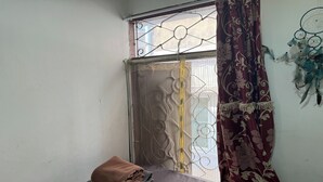 A room with a bed, a window with metal bars, and a curtain. - Sleep Break Hostel Sathon (Bangkok)