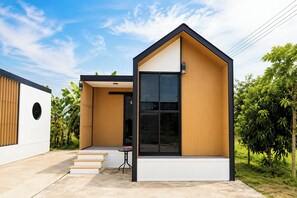 A modern house with a large window, a small porch, and a staircase leading to the entrance.