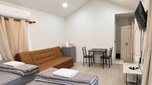 Ein gemütlicher Raum mit einem Bett, einer Couch, einem kleinen Tisch mit Stühlen und einem an der Wand befestigten Fernseher.