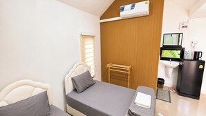 Ein kleines Hotelzimmer mit Bett, Schreibtisch, Spüle und Kühlschrank.
