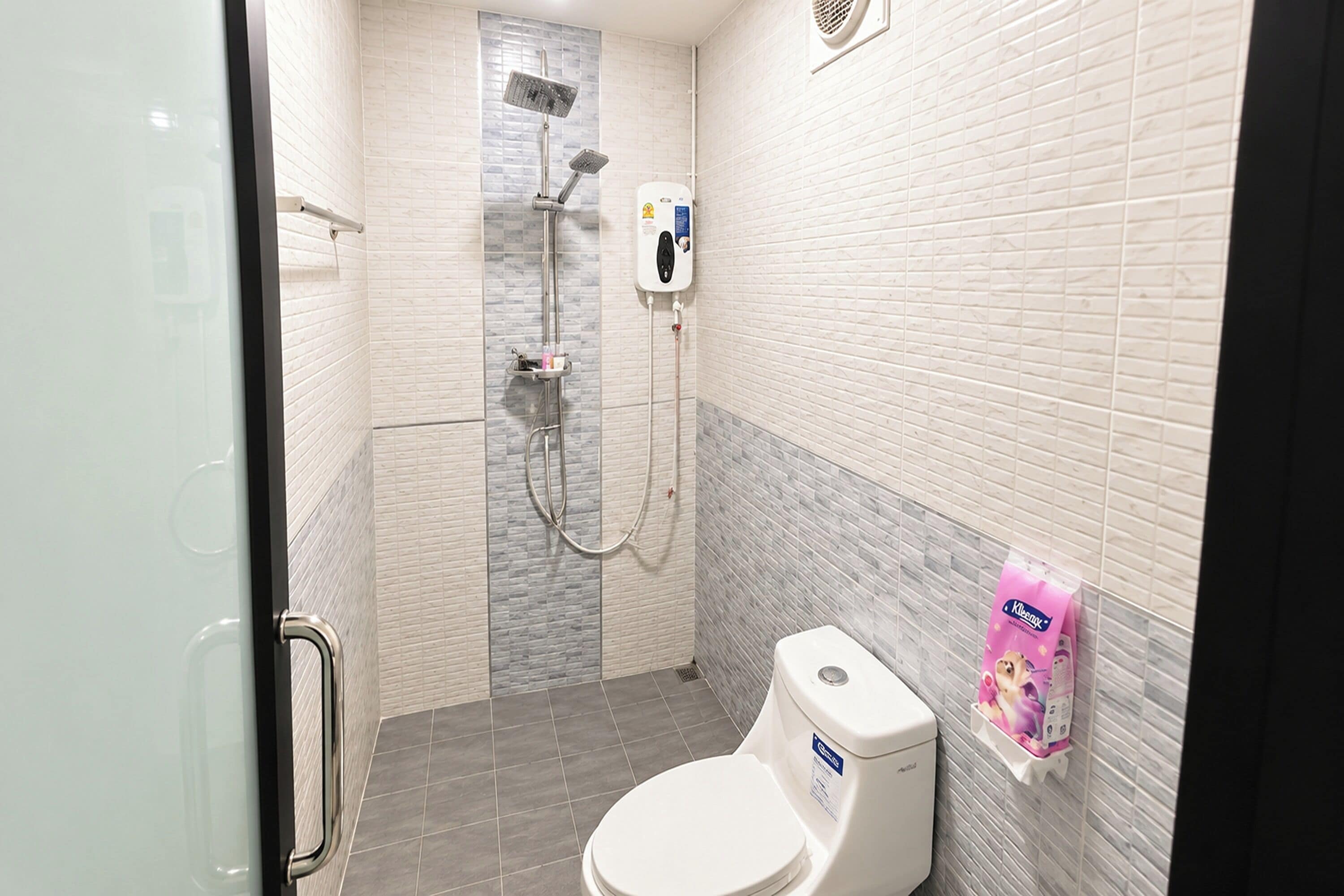 A bathroom with a toilet, a shower, and a hand dryer.