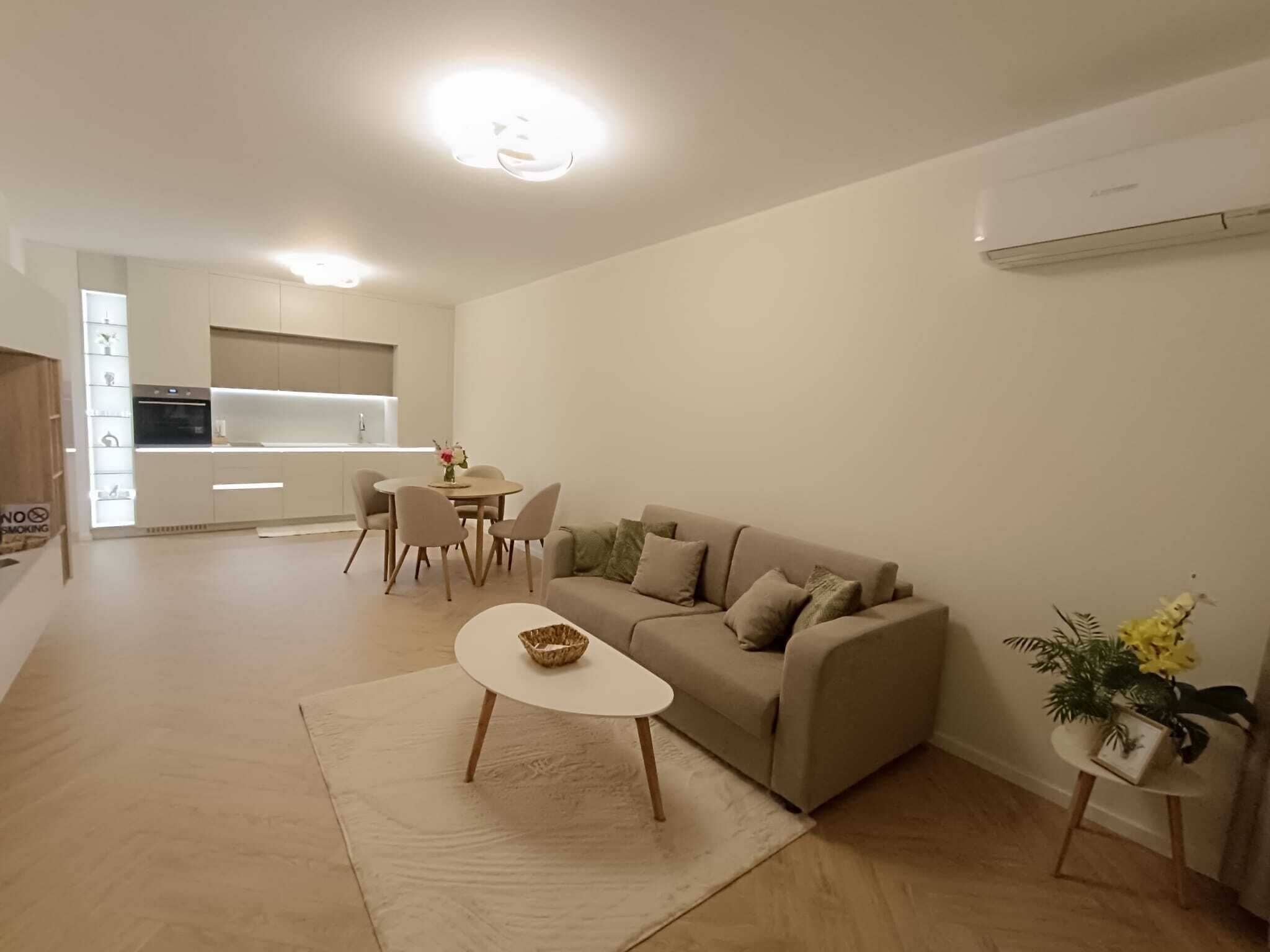 A modern living room with a sofa, coffee table, and dining area.