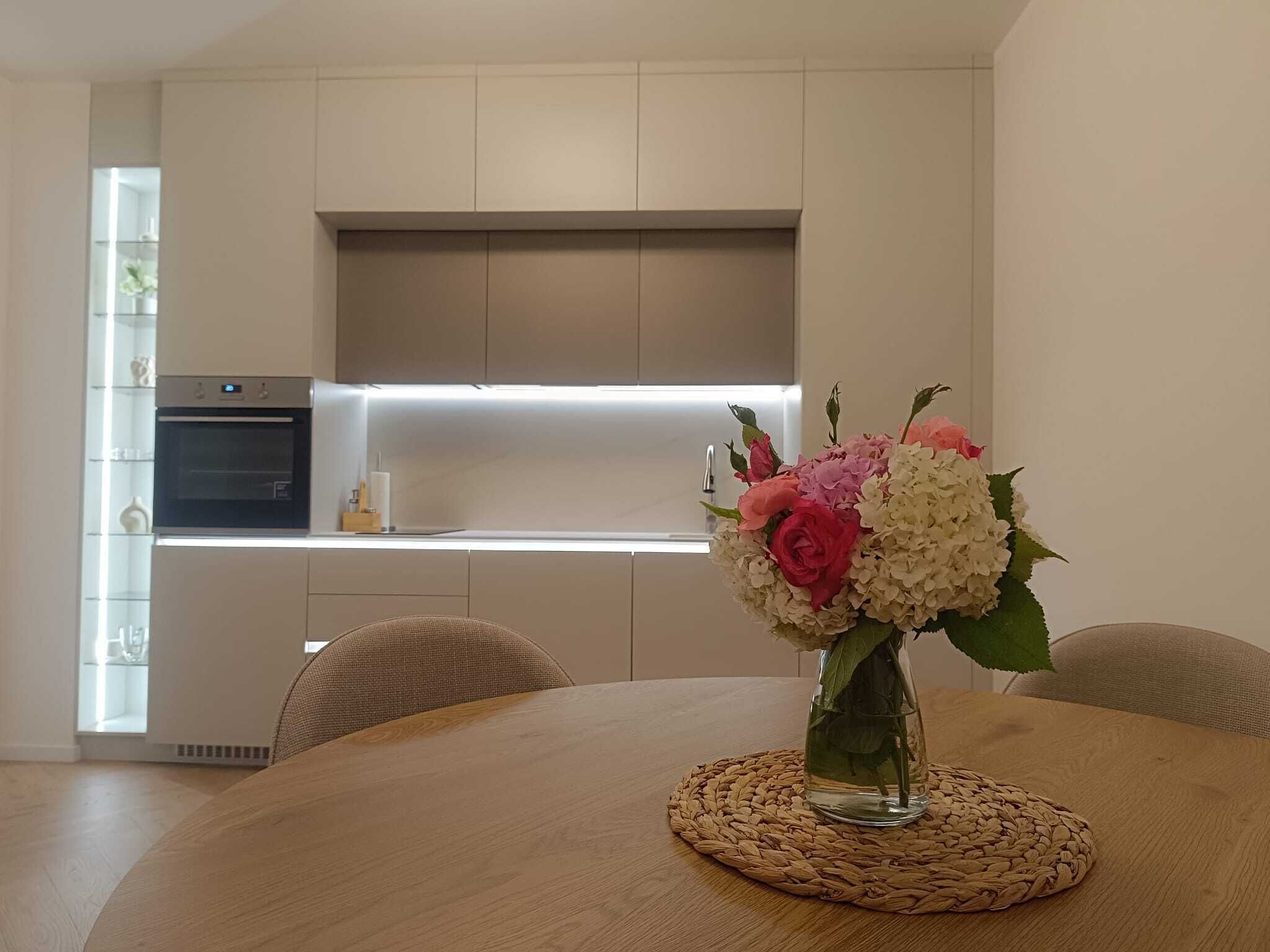 A modern kitchen with a built-in oven and a dining area with a round table and chairs.