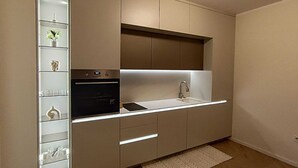A modern kitchen with built-in appliances, a countertop sink, and a backsplash. - Helena Living Harmony (Varna)