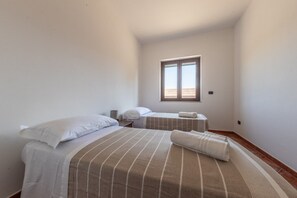A small, clean room with two beds, a window, and a plain wall. - Hospitality as a Value: ​There are places that keep alive the spirit of those who loved them. (Giardoni)