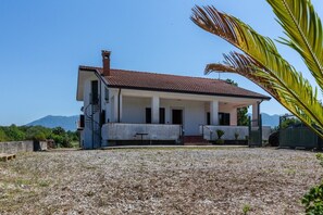A two-story building with a tiled roof, a covered porch, and a staircase leading to the upper floor. - Hospitality as a Value: ​There are places that keep alive the spirit of those who loved them. (Giardoni)