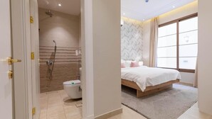 A modern bathroom with a shower, toilet, and a bed with a view of the outside.