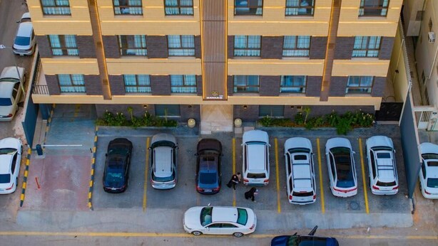 An aerial view of a multi-story building with a parking lot in front.