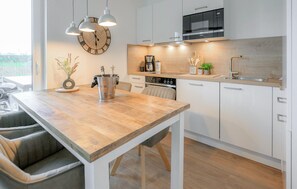 Eine moderne Küche mit Holztisch, weißen Schränken, Backofen und Siemens-Mikrowelle.