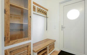 Ein Zimmer mit weißer Tür, einer Sitzbank und einem Kleiderständer mit Haken.