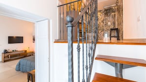 A modern staircase with a metal railing and wooden steps, leading to a room with a bed and a TV. - Residenza Partanna by Napoliapartments (Naples)