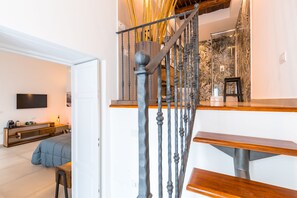 Eine moderne Treppe mit Metallgeländer und Holzboden, die zu einem Zimmer mit Bett und Fernseher führt.