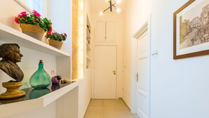 A hallway with a white door, shelves with decorative items, and a framed picture on the wall. - Residenza Partanna by Napoliapartments (Naples)
