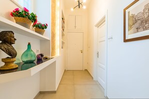Ein Flur mit einer weißen Tür, Regalen mit Dekoration und einem gerahmten Bild an der Wand.