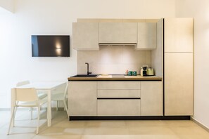 Eine moderne Küche mit Flachbildfernseher, einem Esstisch mit Stühlen und einem eingebauten Backofen.