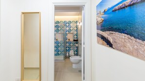 Et badeværelse med bruser, toilet og dekorativ væg.