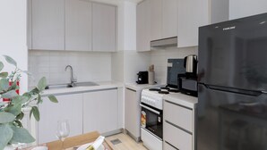 A modern kitchen with white cabinetry, a black refrigerator, a coffee maker, and a microwave.
