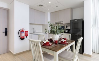 Una cocina moderna con armarios blancos, un refrigerador negro y una mesa de comedor con vajilla roja.
