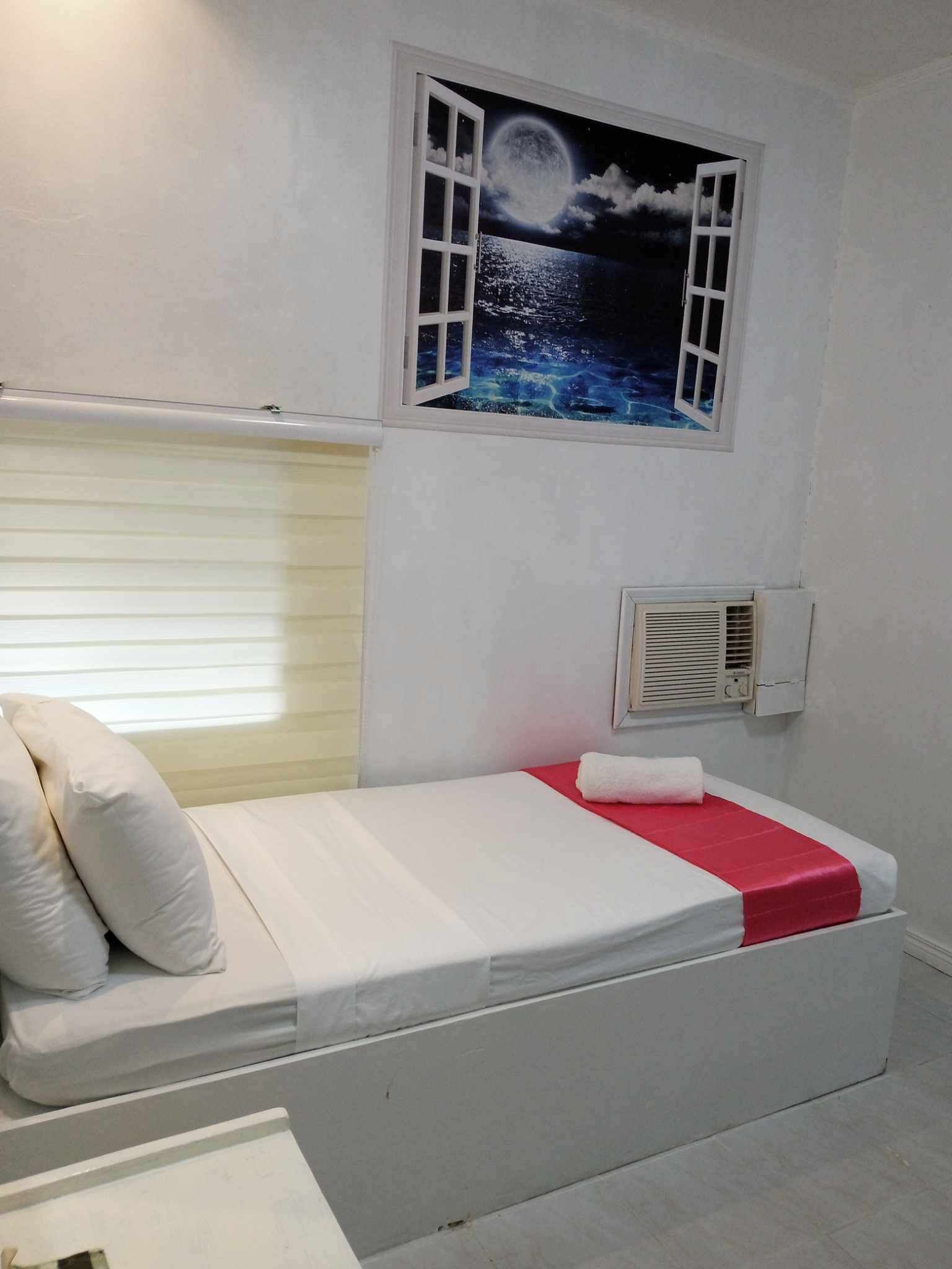 Camera singola con un letto, una finestra affrescata con un cielo stellato, un comodino e un condizionatore d'aria a parete.
