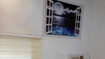 Camera singola con un letto, una finestra affrescata con un cielo stellato, un comodino e un condizionatore d'aria a parete.