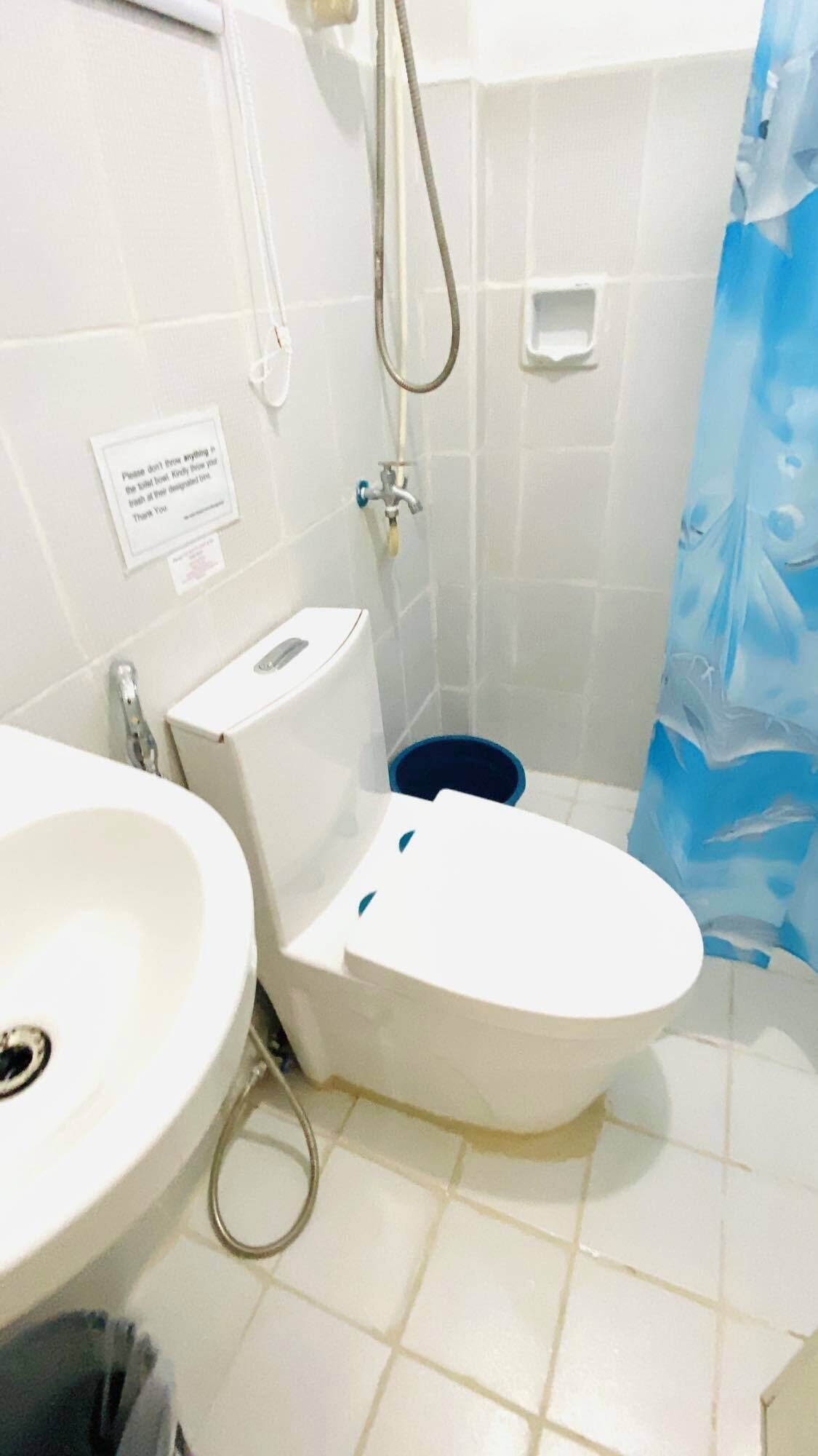 A bathroom with a toilet, sink, shower, and a blue curtain.